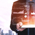 Immagin virtuale di una persona che regge tra le mani un computer portatile che mostra sullo schermo diagrammi e infografiche di marketing.