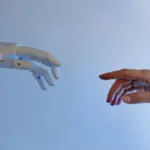 Immagine virtuale di una mano umana e una mano robotica viste di lato che stanno per toccarsi.