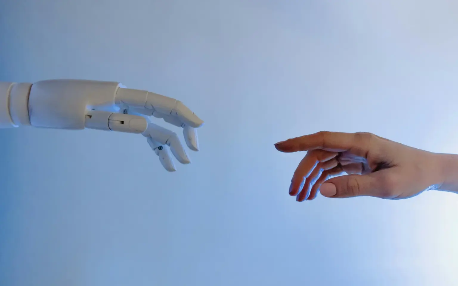 Immagine virtuale di una mano umana e una mano robotica viste di lato che stanno per toccarsi.