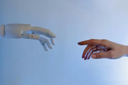 Immagine virtuale di una mano umana e una mano robotica viste di lato che stanno per toccarsi.