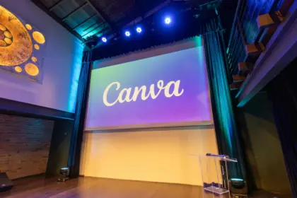 Palco di un teatro allestito per un evento di formazione con un maxischermo che mostra il logo di Canva