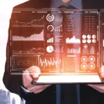 Immagine virtuale di una persona che regge tra le mani un computer portatile che mostra sullo schermo diagrammi e infografiche di marketing.