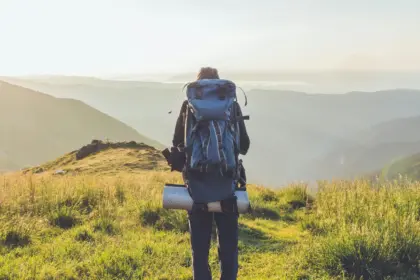 Persona con abbigliamento tecnico e zaino da trekking visto di spalle su un sentiero in mezzo agli appennini