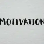 Scritta "Motivation" scritta a mano con un pennello a tempera nera su una tela canvas bianca
